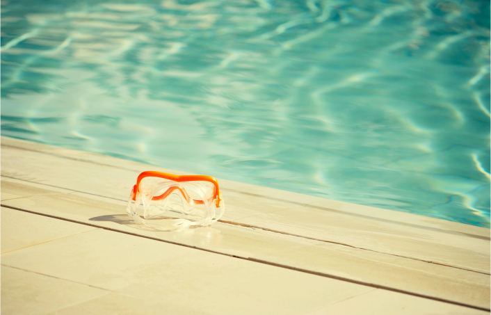 Orange swimming goggles lying poolside.