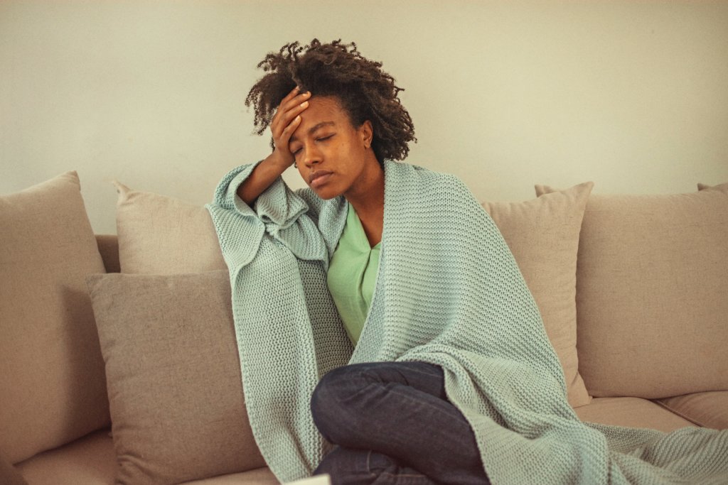 Woman sitting on sofa suffering from chikungunya fever.