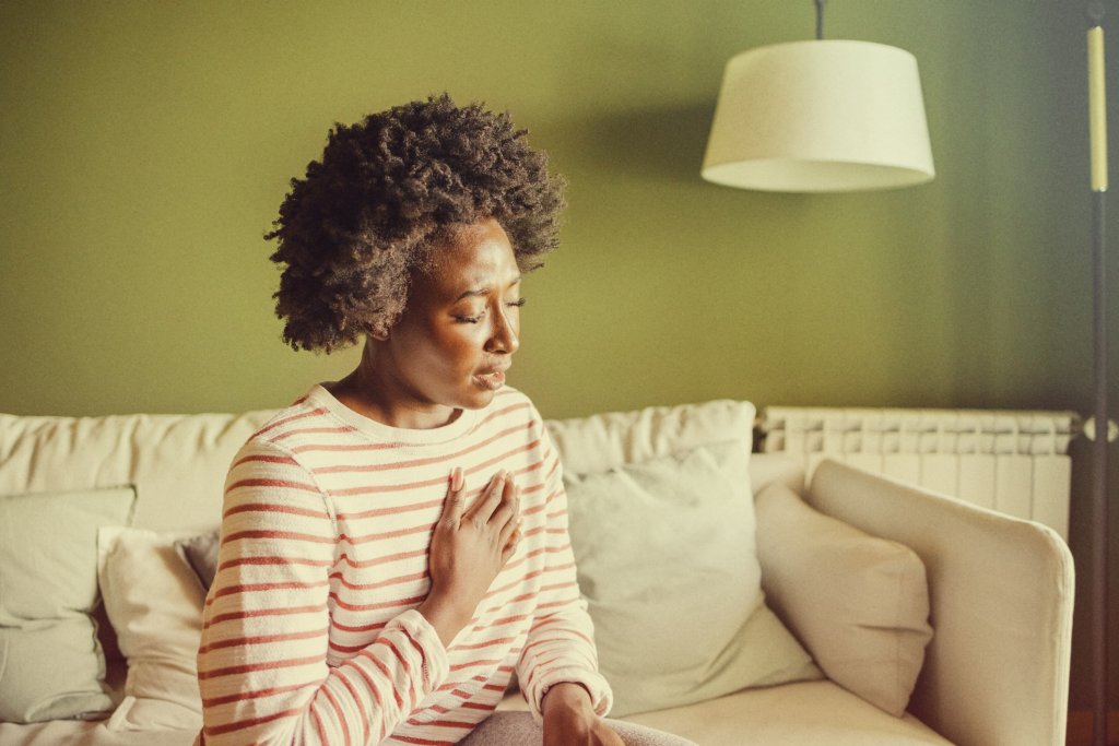 Woman clutching at heart, suffering long term effects of chikungunya.
