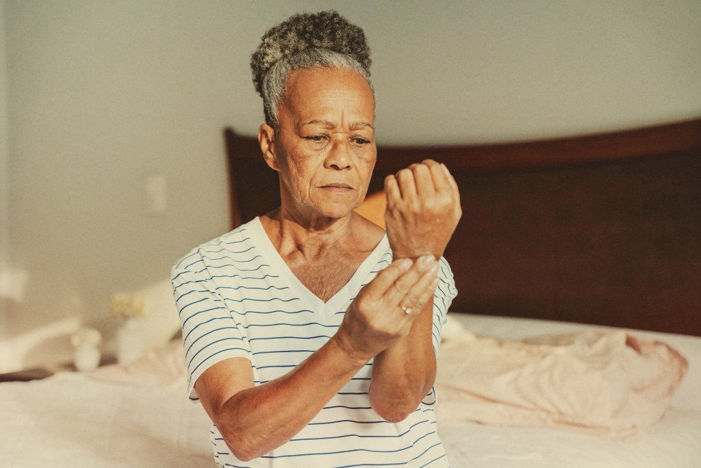 Woman suffering from chikungunya joint pain examining her wrist, a common symptom.