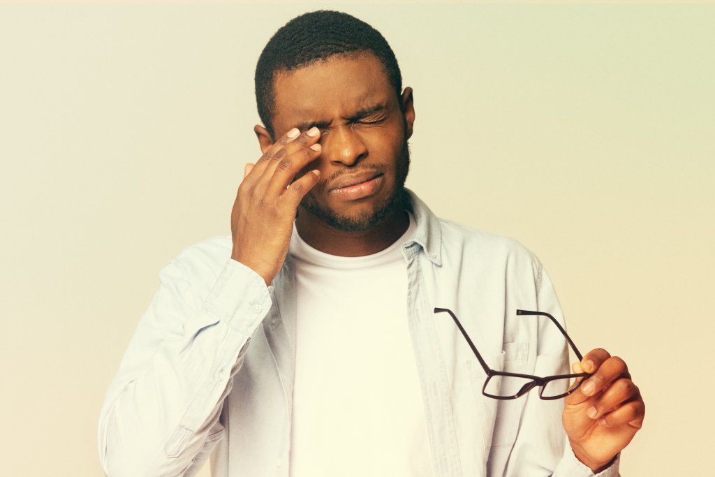 Man rubbing his eye, suffering from chikungunya long term effects.