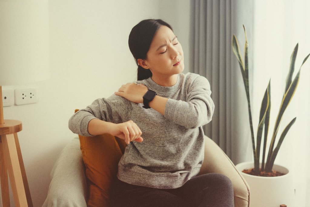Person rubbing sore muscles, a symptom of chikungunya.