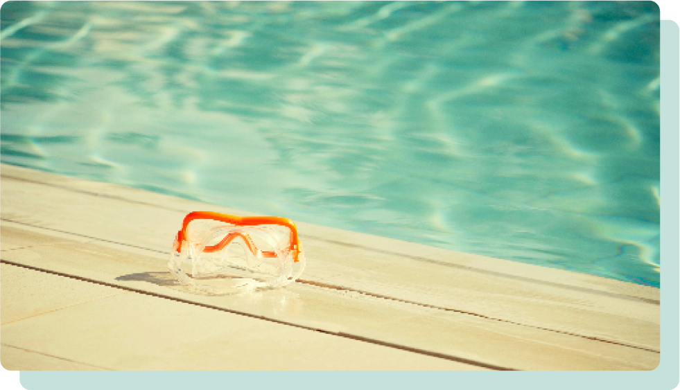 Orange swimming goggles lying poolside.